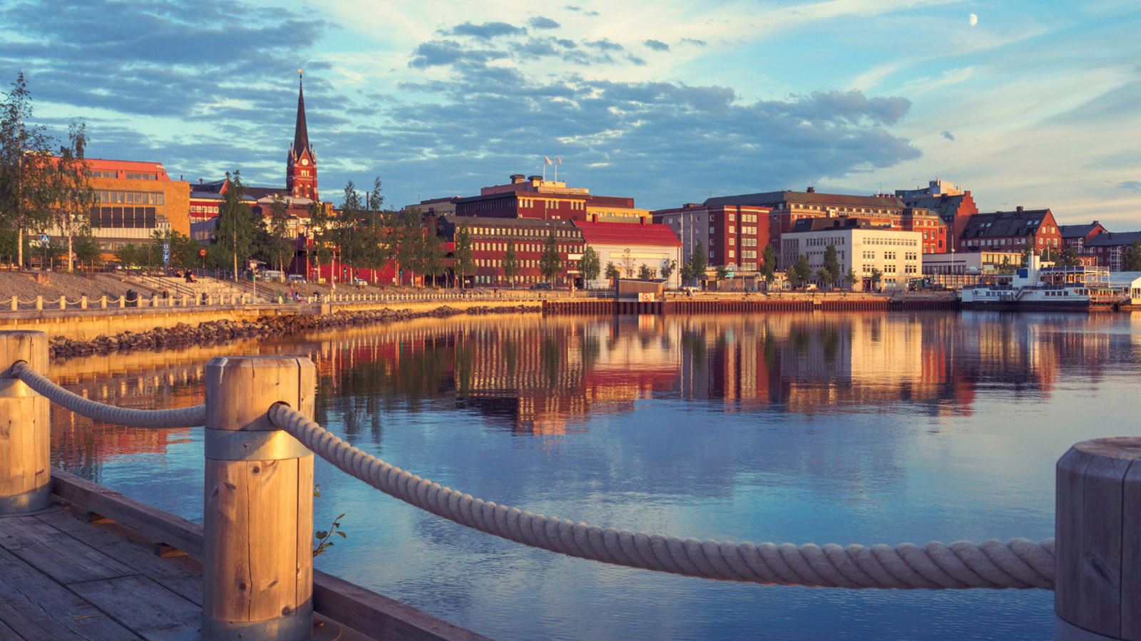 En stad där bilden är tagen i solnedgången och en stillsamt vatten framför alla byggnader.