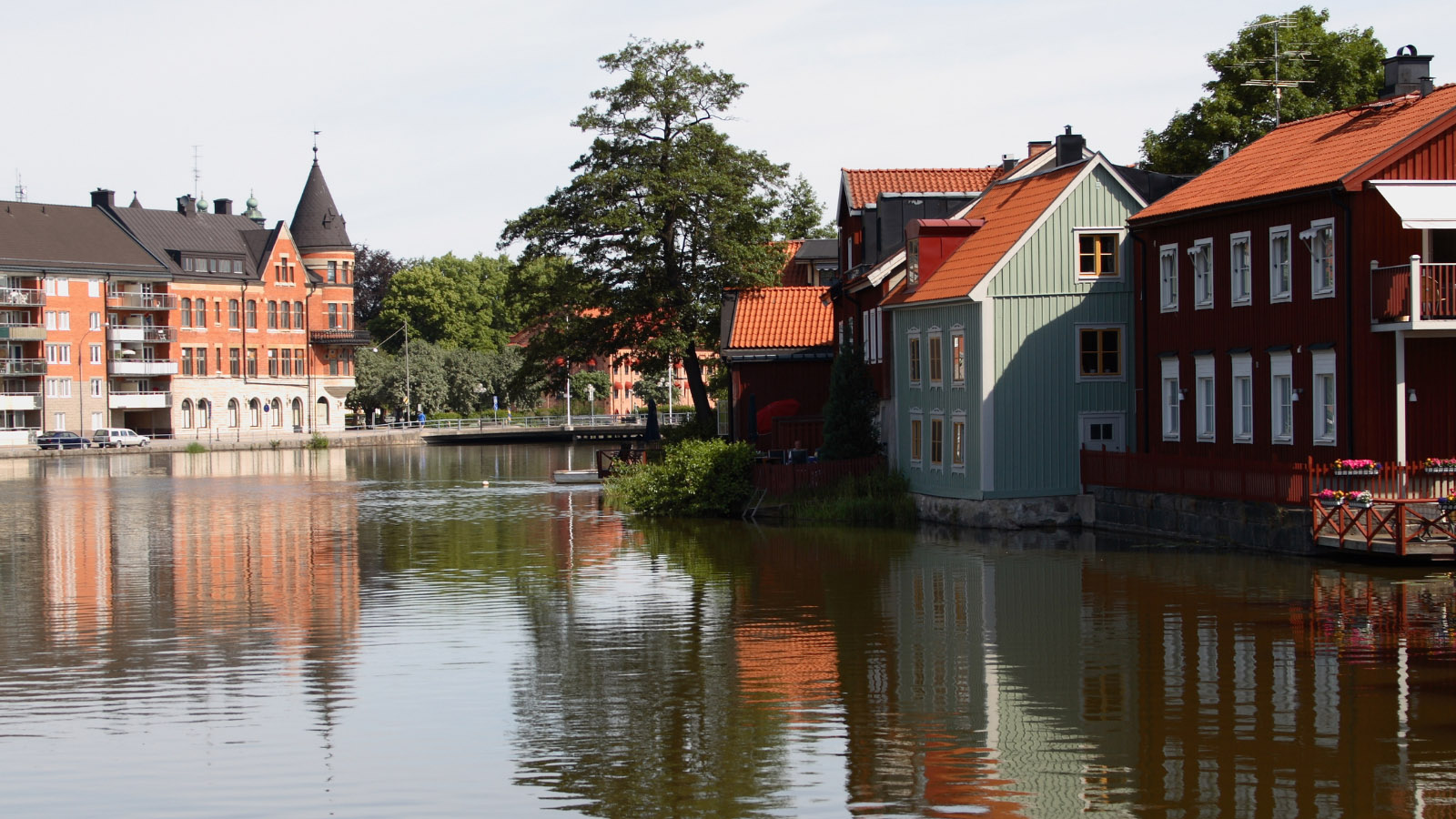 Vid vattnet ligger det några gamla trävillor i rött och grönt och ett större bostadshus i tegel i sekelskiftesstil.