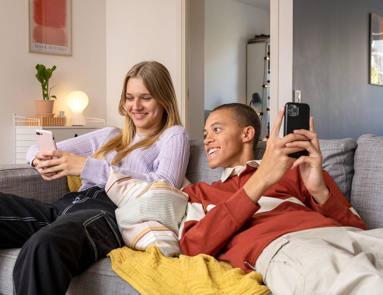 En tjej och kille sitter i en soffa i en Heimstaden lägenhet och registrerar sig som sökande.