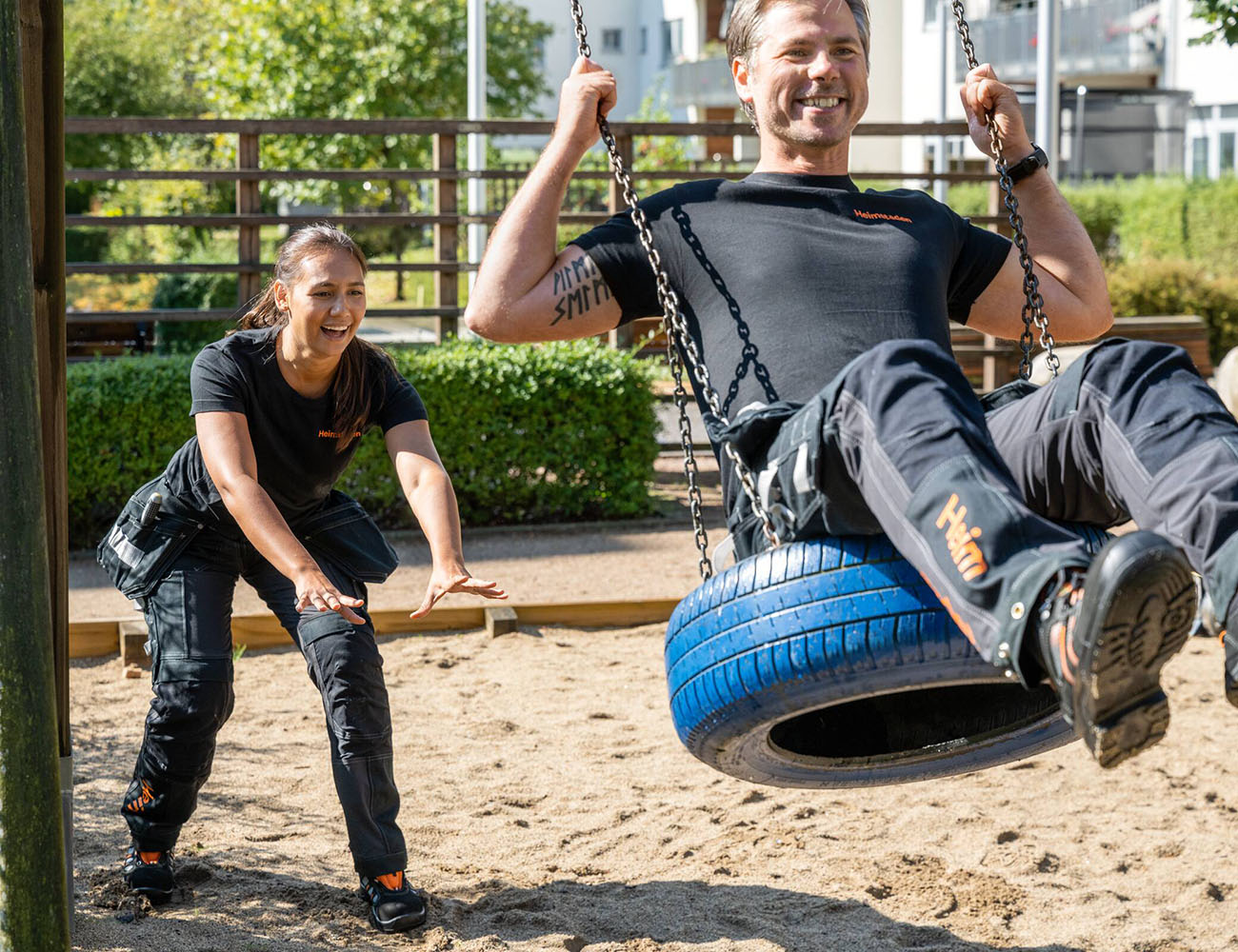 Två fastighetsskötare från Heimstaden gungar i en lekplats i Värnamo.