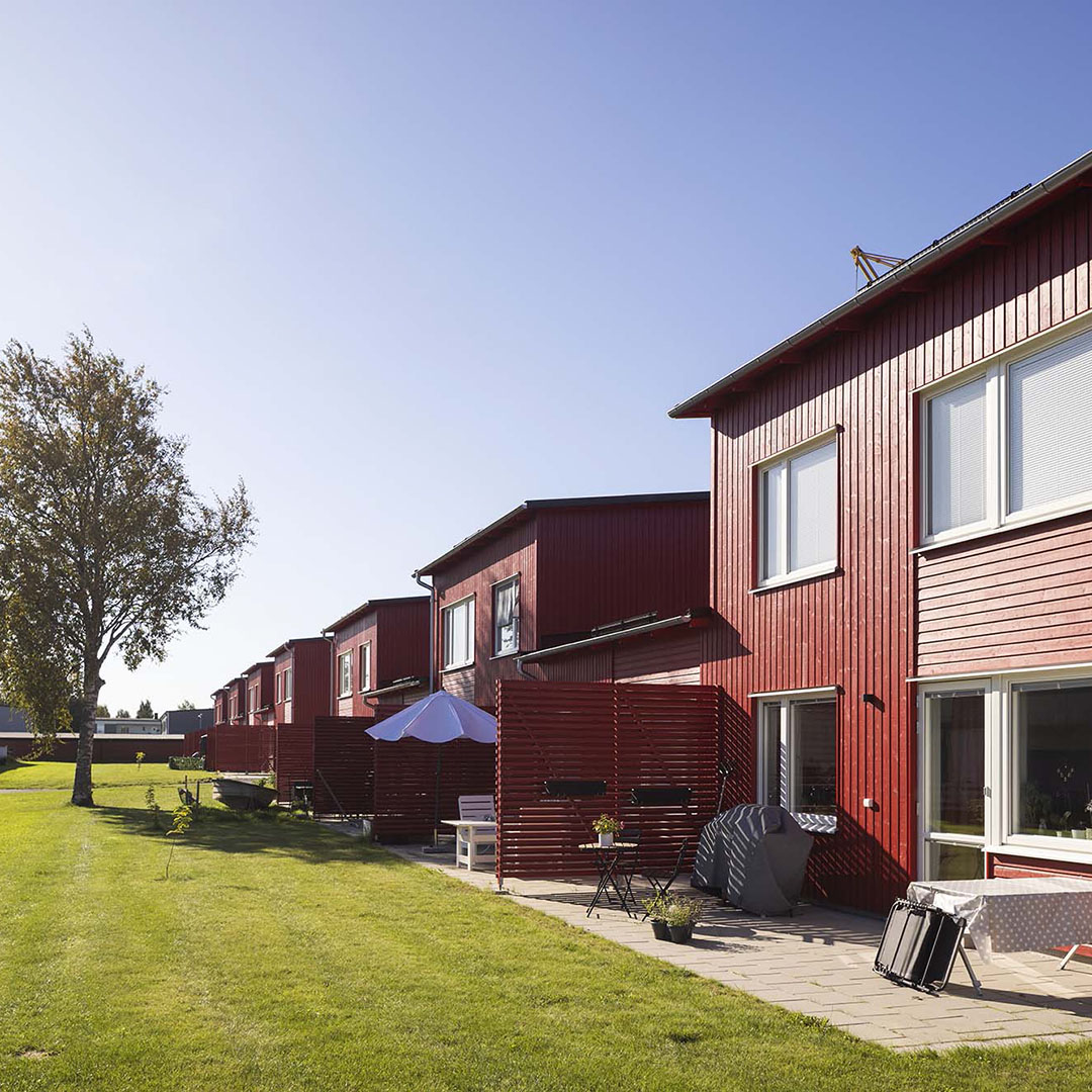 En röd träfasad i solsken i Skellefteå där Heimstaden erbjuder lediga lägenheter.