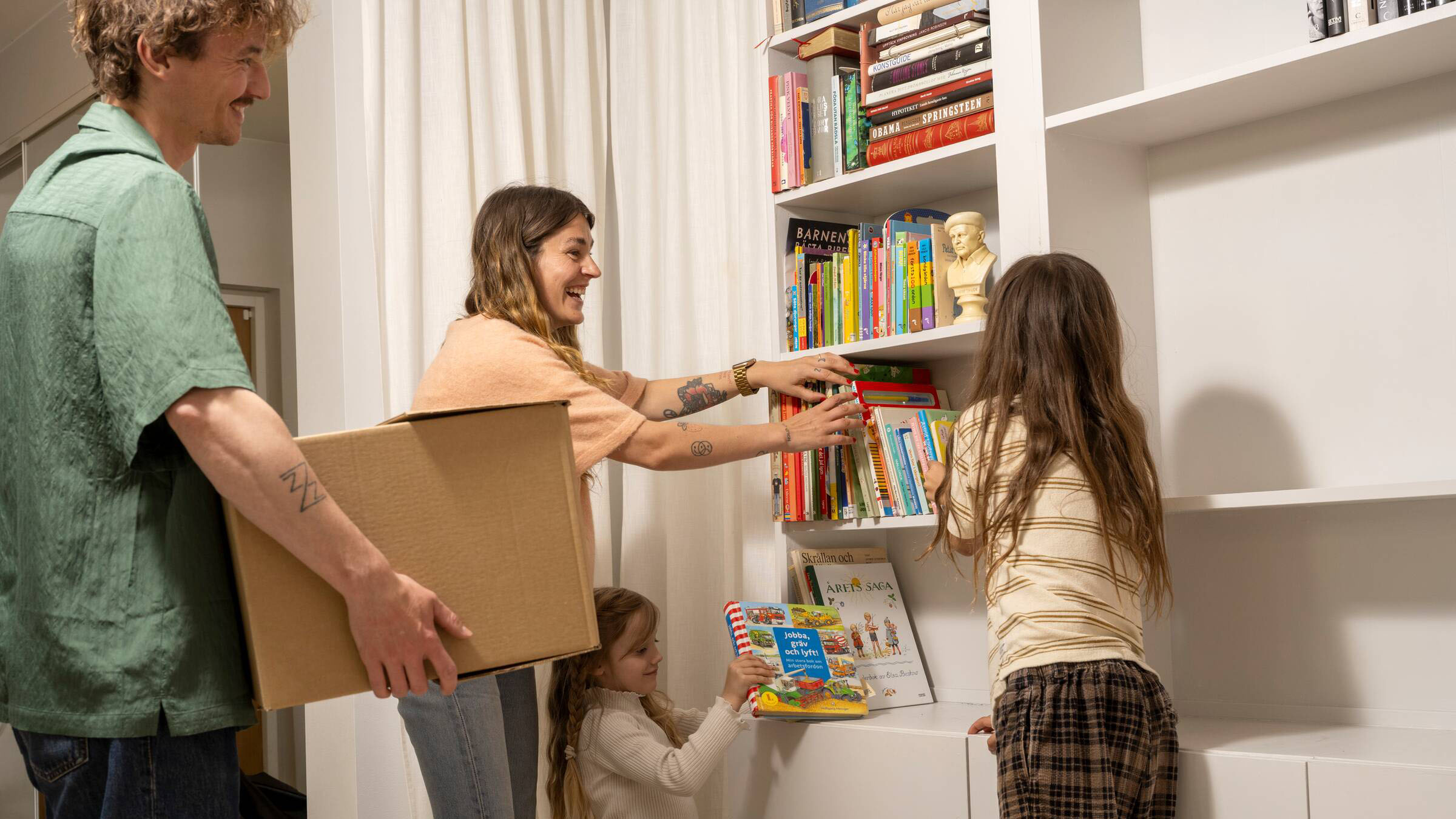 En familj som precis flyttat in i en Heimstaden lägenhet packar upp och ställer in böcker i bokhyllan.
