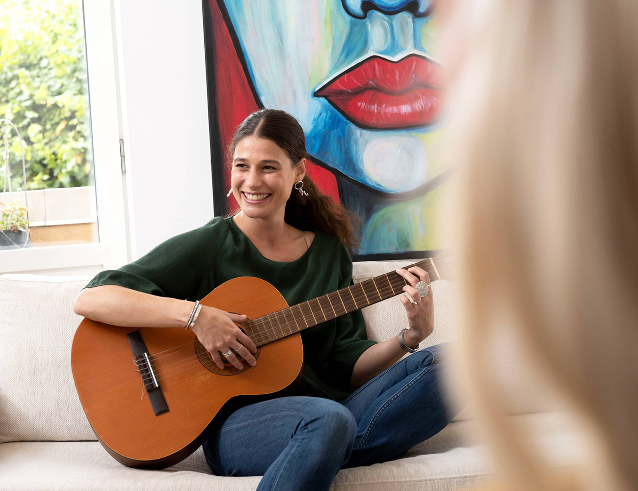 En kvinnlig student sitter i en studentlägenhet hos Heimstaden och spelar gitarr.