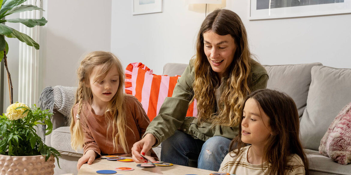 En mamma och två barn sitter i en soffa i en Heimstaden lägenhet och spelar spel.