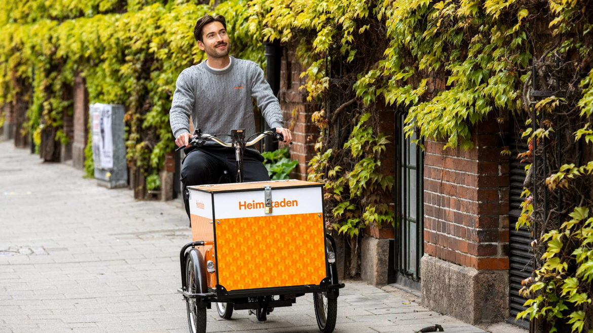 Man cyklar på en Heimstaden lådcykel på en trottoar i Malmö.