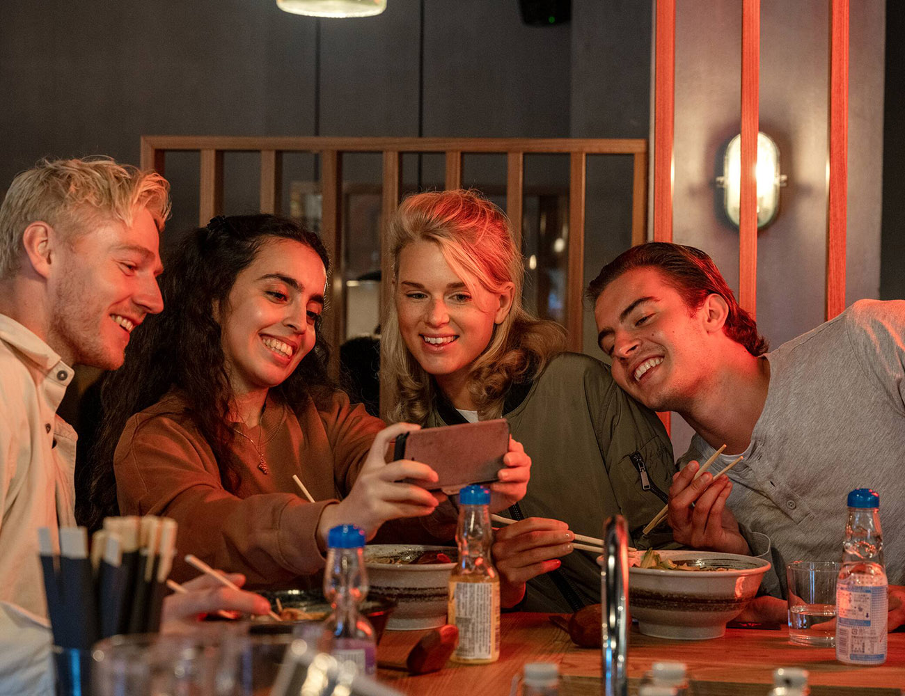 Fyra ungdomar sitter på en restaurang och tar en selfie.