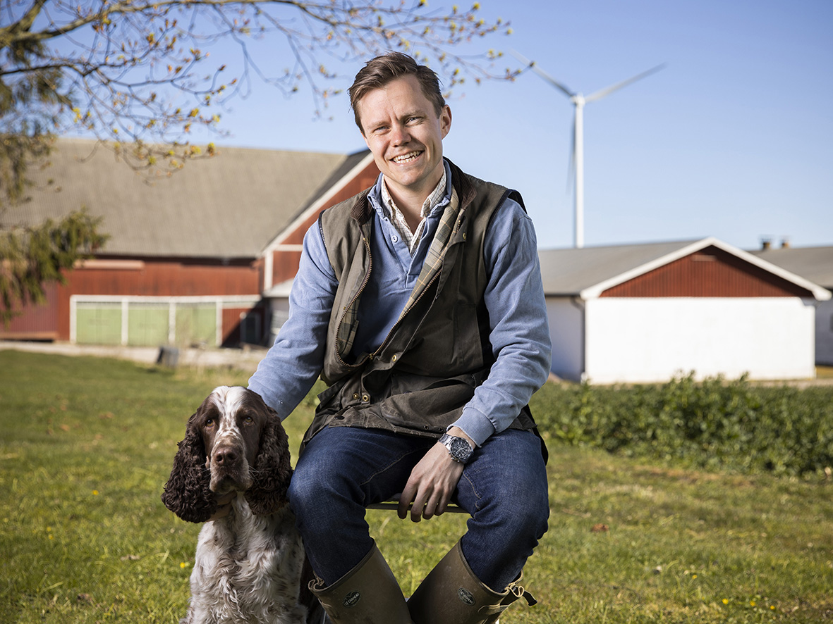 A man is sitting with his dog in front of a farm house