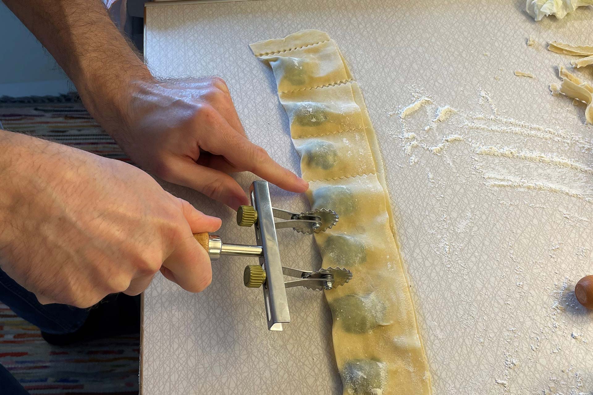 Someone is cutting the ravioli dough into ravioli.