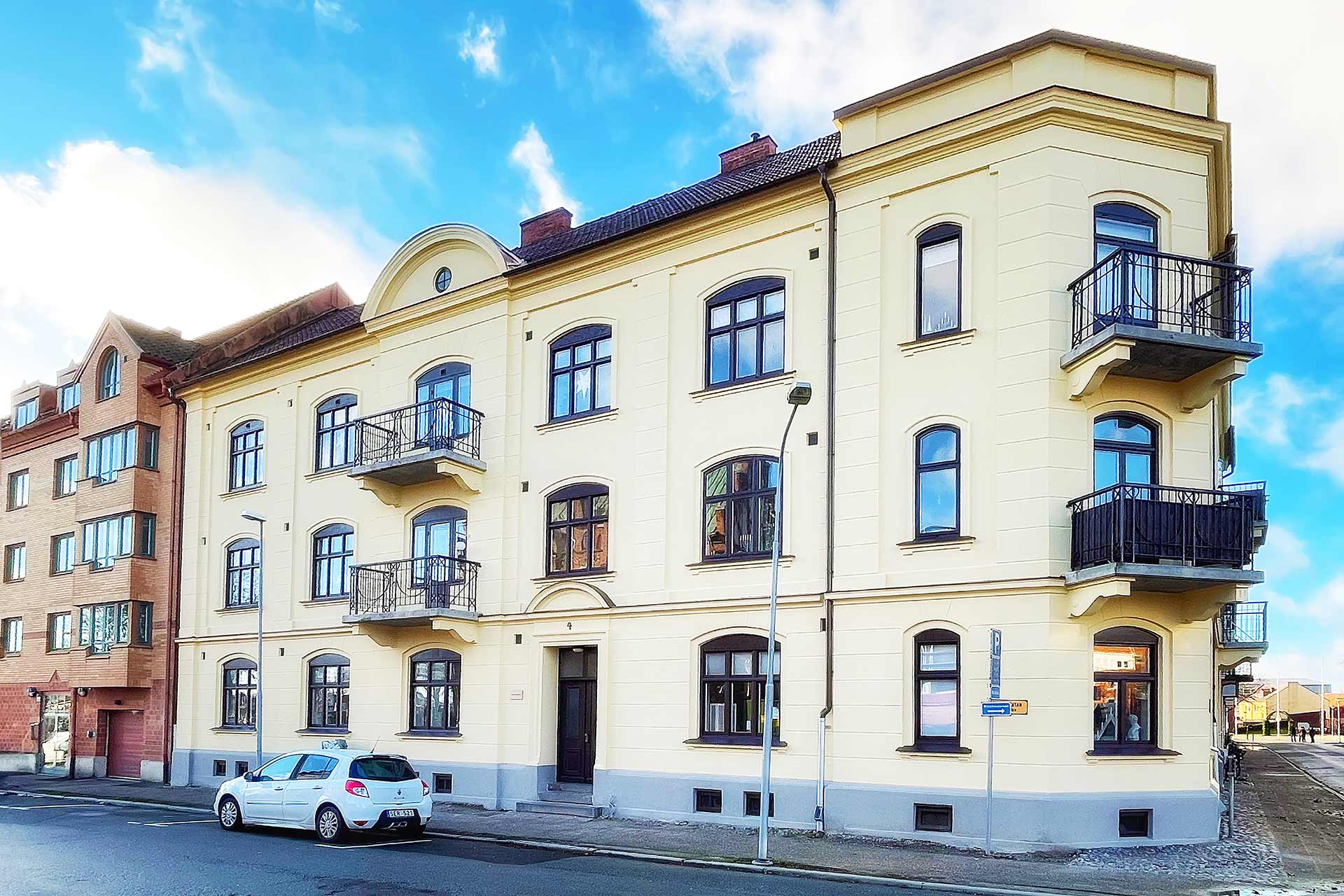 A big yellowish-white house with balconies and many windows against a blue sky.