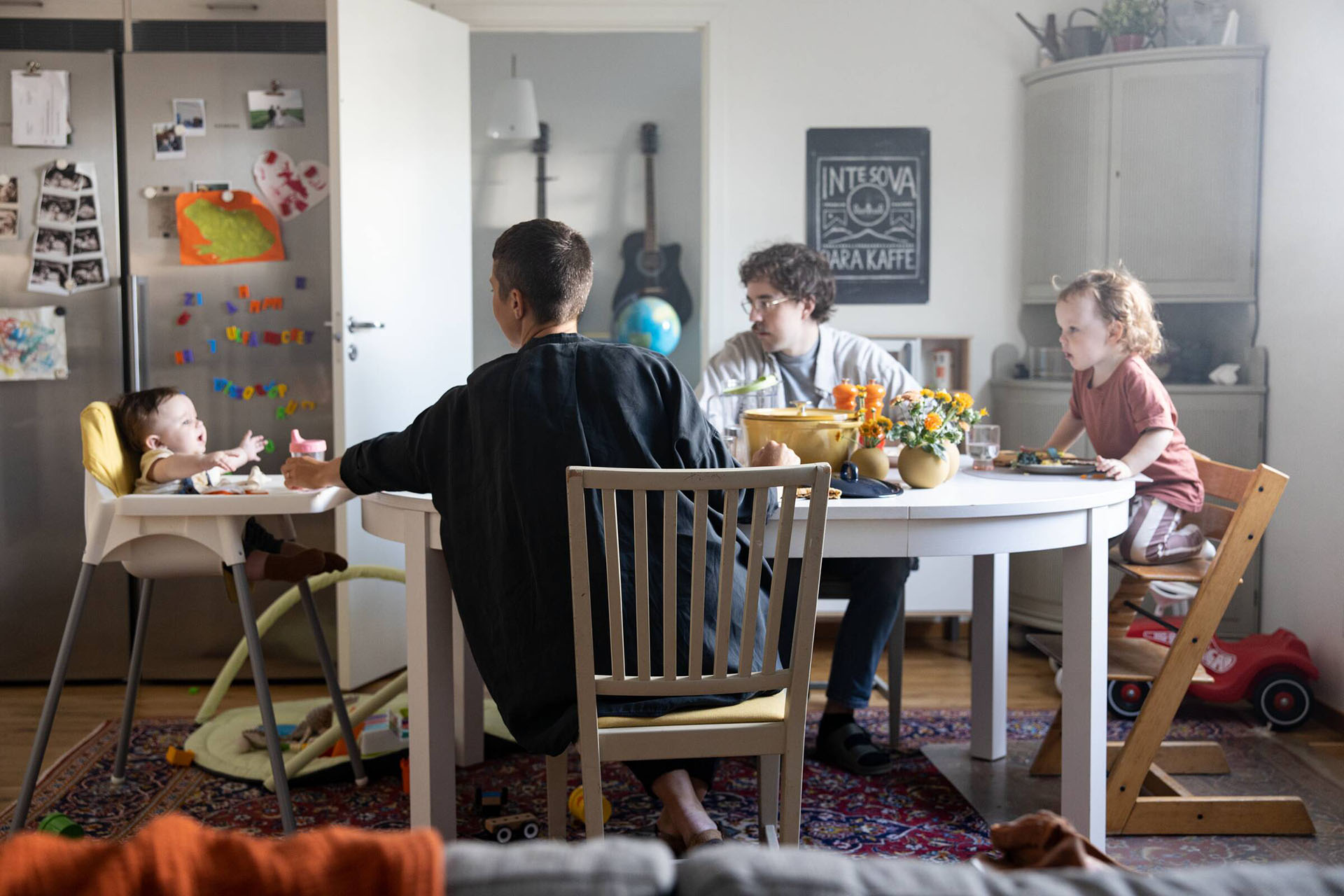 En familj med småbarn sitter vid sitt köksbord och äter mat