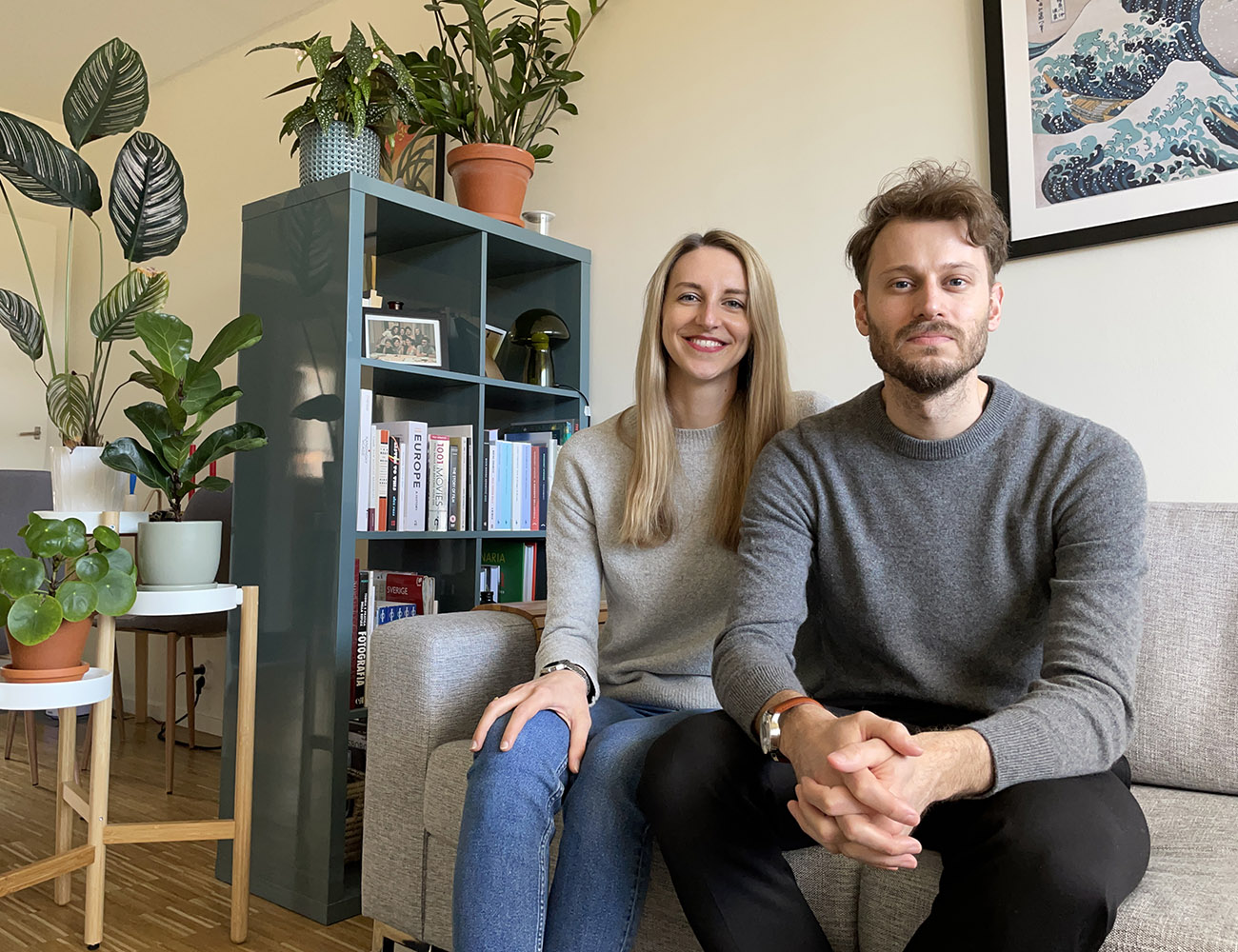 A blonde woman in a beige sweater and a man in a brown sweater are sitting on a coach in a livingroom.