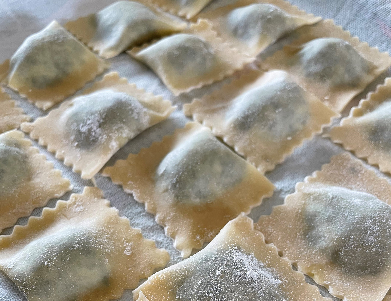 Several tortellinin with filling are lying on a table. They have been prepared, but not yet cooked.