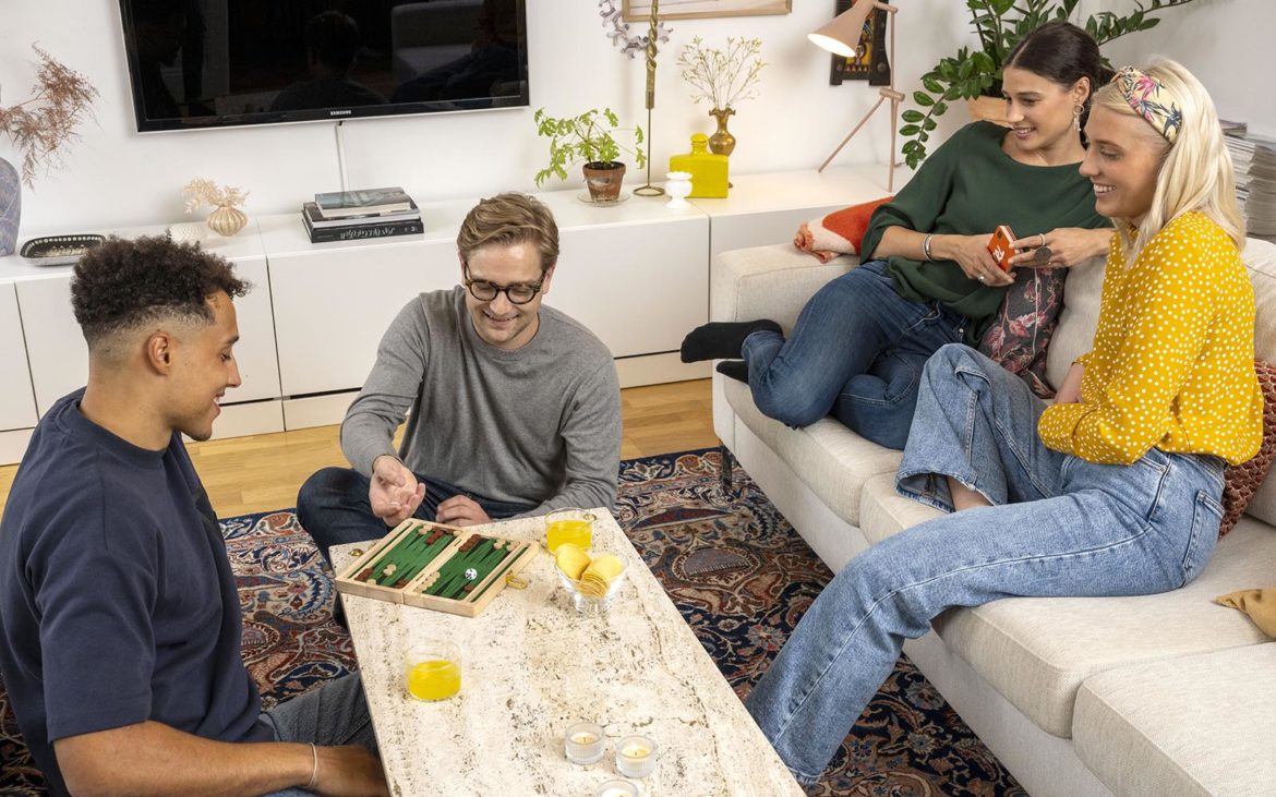 Two boys and two girls are sitting on the couch and on the floor playing games.