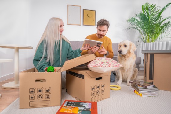 couple packing moving boxes with dog