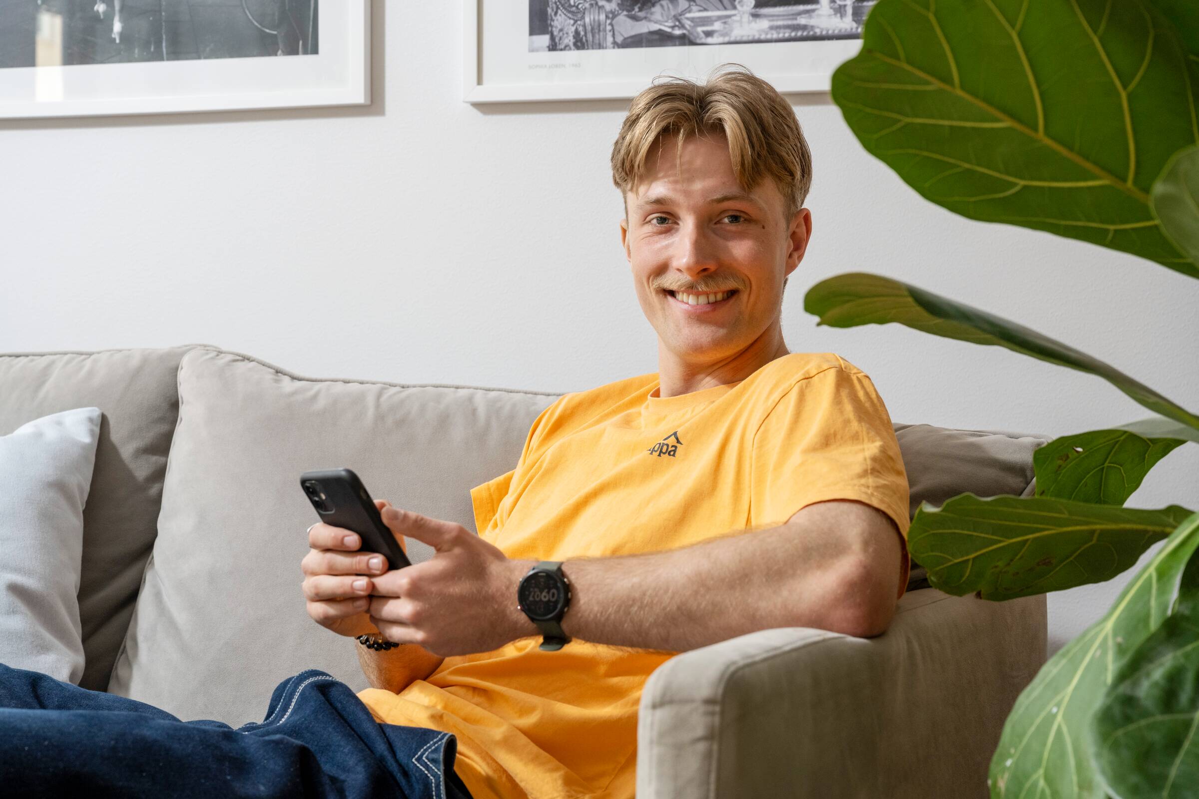 Mann sitter i sofaen med telefonen sin