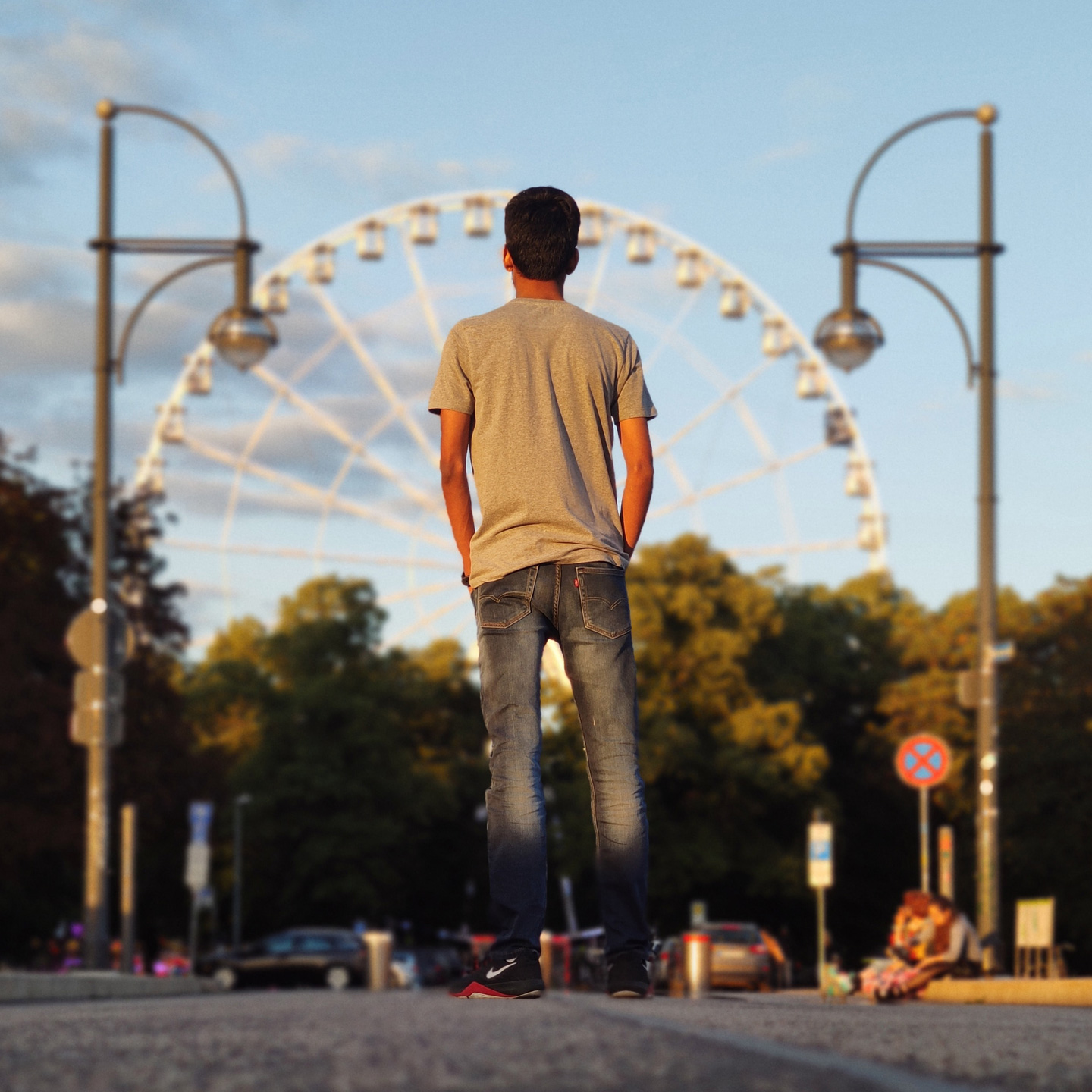 Riesenrad im Hintergrund in Magdeburg mit jungen Mann im Vordergrund; abendliche Stimmung