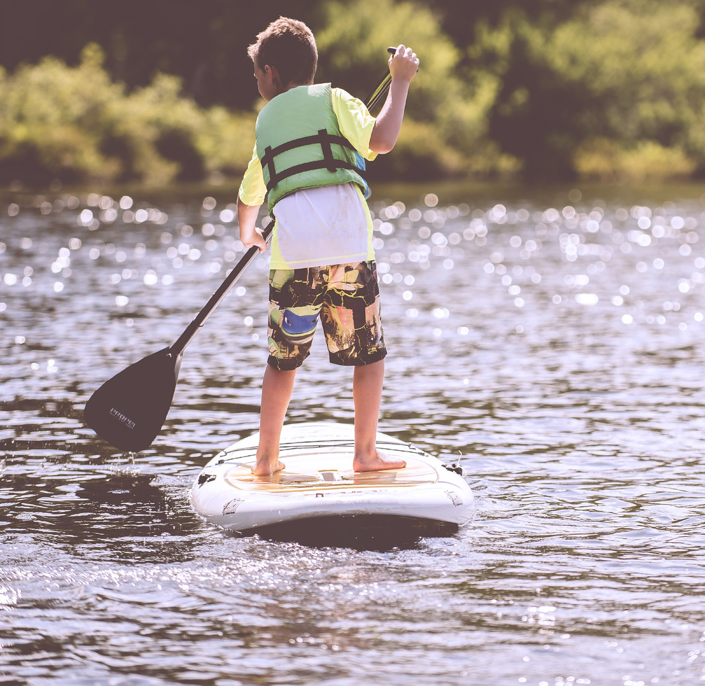 Junge steht auf SUP im Alperstedter See und paddelt