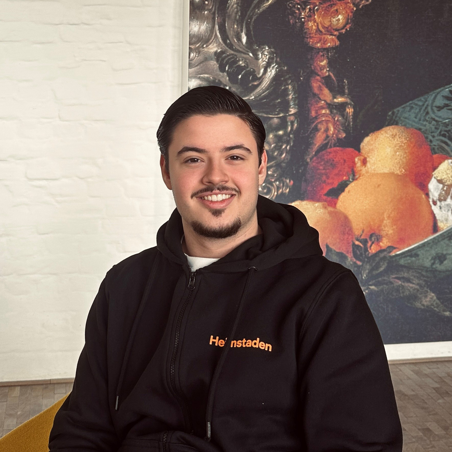 Azubi von Heimstaden im Büro vor Wand mit Gemälde